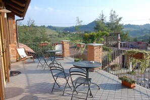 Une terrasse avec des sièges extérieurs, une vue sur la campagne et un mur en briques.