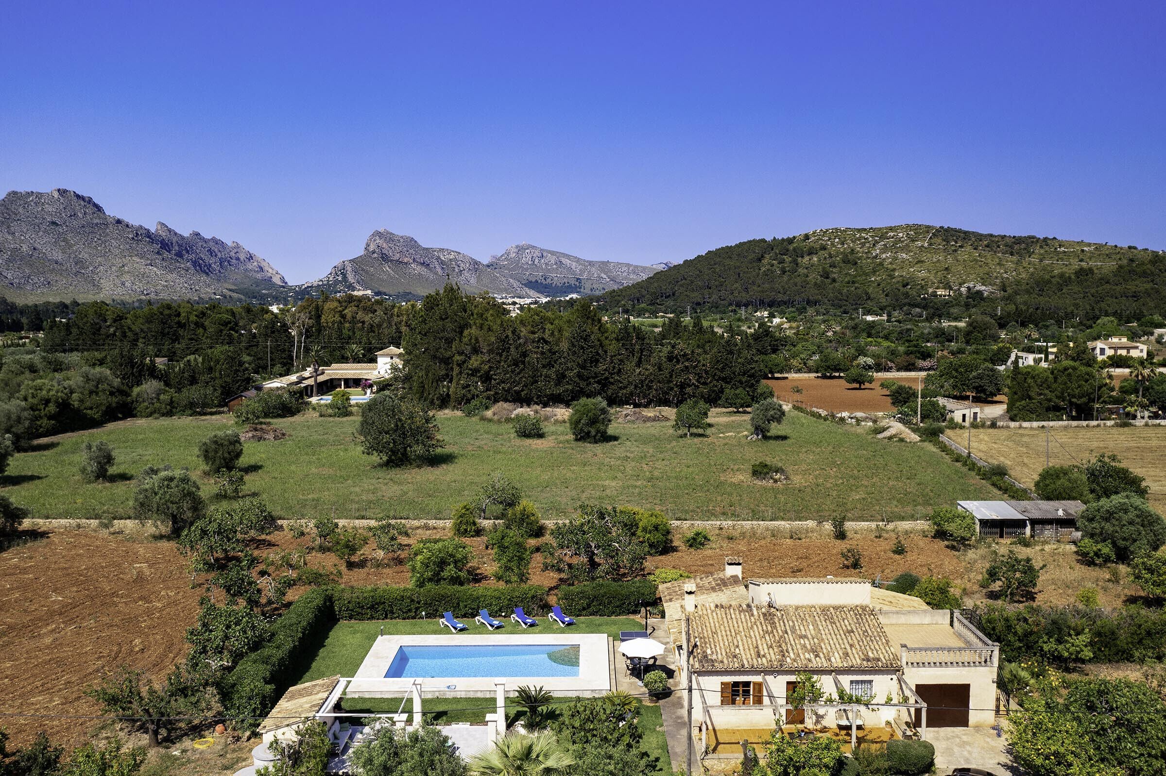 Eine Villa mit Swimmingpool, umgeben von grünen Feldern und Bergen.