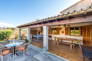 Une terrasse extérieure avec une table de ping-pong, une table à manger et des chaises en osier.