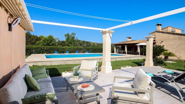 Une terrasse avec mobilier d’extérieur, une piscine et une vue sur le paysage environnant.