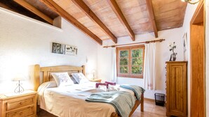 Une chambre à coucher avec un lit en bois, une table de chevet, une armoire et une fenêtre avec des rideaux.