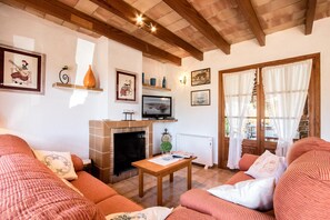 Un salon chaleureux avec une cheminée, des poutres en bois et un téléviseur.