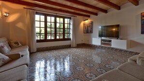 A living room with a large window, a flat-screen TV, and patterned floor tiles. - GRAN VORAMAR CALA. 200 m2 pool and 6 bedrooms (Cala San Vicente)