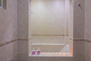 A bathroom with beige tiles, a bathtub, two pink soap dispensers, and a row of lit candles. - 2 Bed Majestic Villa Near Beach (Pattaya)