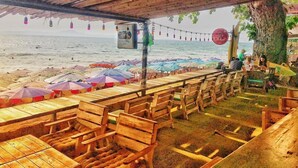 A beachside restaurant with wooden tables and chairs, umbrellas, and a view of the ocean. - 2 Bed Majestic Villa Near Beach (Pattaya)