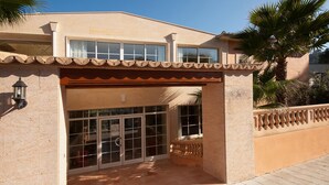 Ein Gebäude mit gefliestem Eingang, großen Glasüren und einem Balkon mit Brüstung.