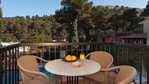 Ein Balkon mit Korbstühlen, einem runden Tisch, einer Schale Orangen und einem Glas Orangensaft.