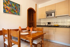 A dining table with chairs, a wooden door, and a kitchen with cabinets and a microwave.