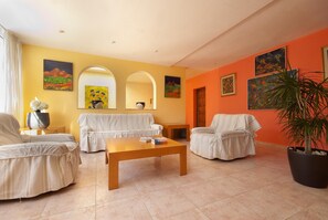 Una sala de estar con sofá, sillones, una mesita de centro y una planta en maceta.