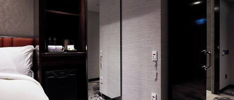 Quarto de hotel com cama, guarda-roupa, espelho e porta.