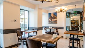 A restaurant with tables and chairs, a painting on the wall, and a chandelier. - The Camelot Hotel (Istanbul)