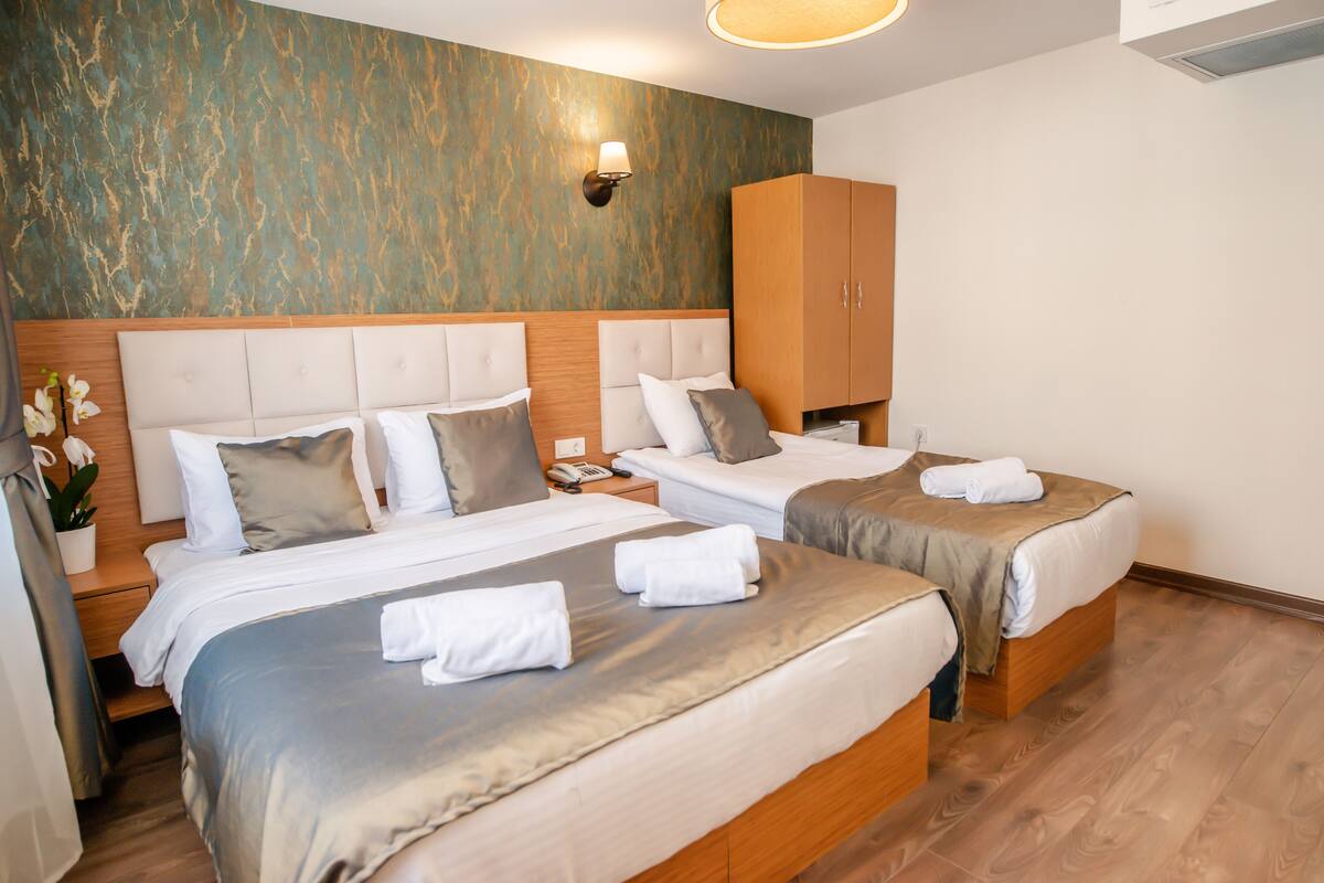 Ett hotellrum med två sängar, trägavlar och en väggmonterad lampa.