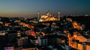A cityscape at dusk with a prominent mosque featuring multiple minarets and a large dome. - The Camelot Hotel (Istanbul)