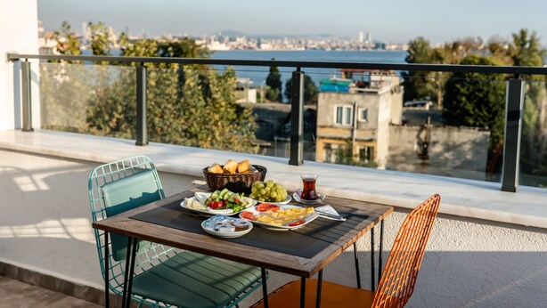A balcony with a table set for breakfast, overlooking a cityscape. - The Camelot Hotel (Istanbul)