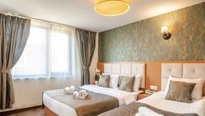 A hotel room with two beds, a wooden headboard, a bedside table with a lamp, and a large window with curtains. - The Camelot Hotel (Istanbul)