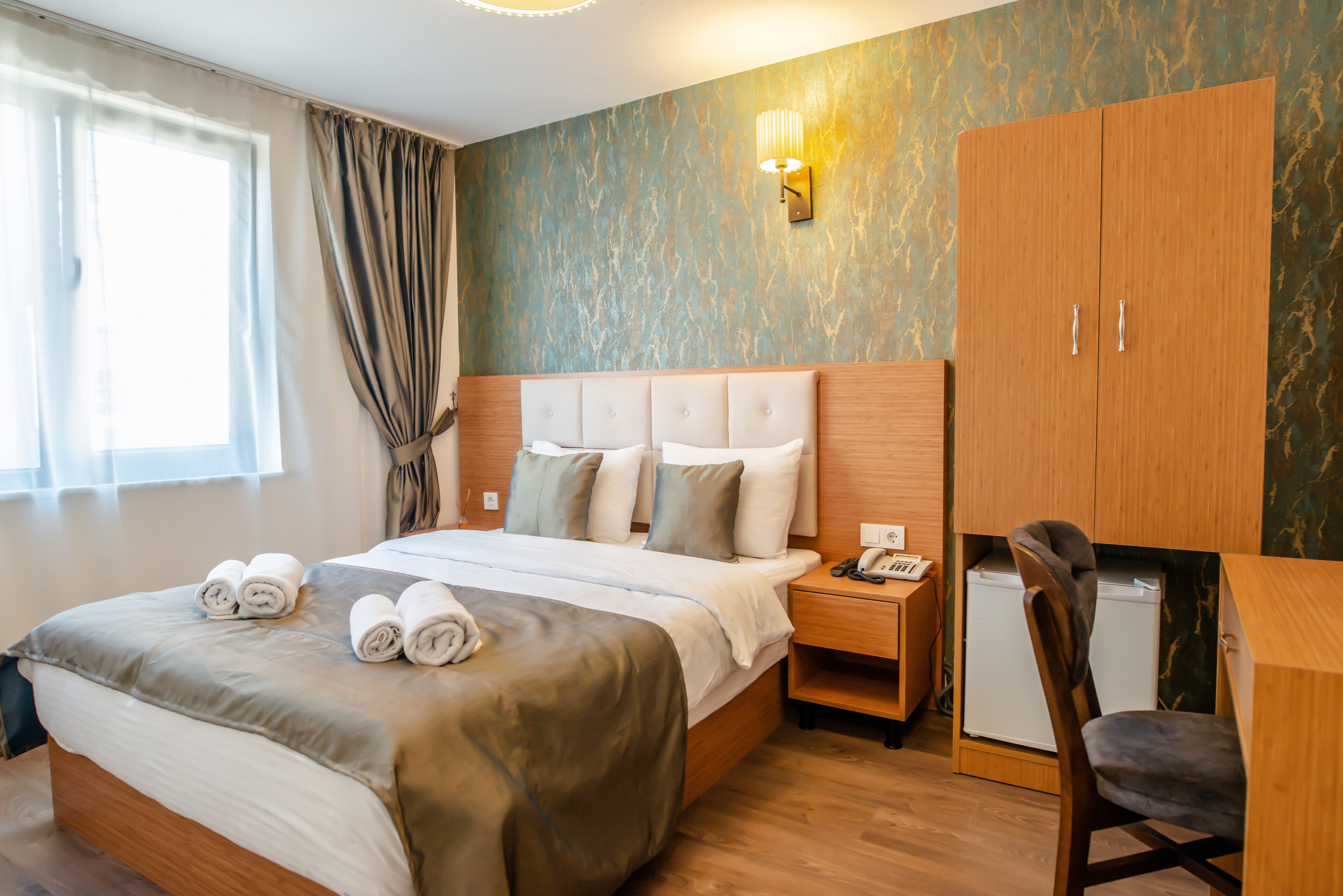 Ein Hotelzimmer mit einem großen Bett, einem Schreibtisch, einem Stuhl, einem Kleiderschrank und einem kleinen Kühlschrank.