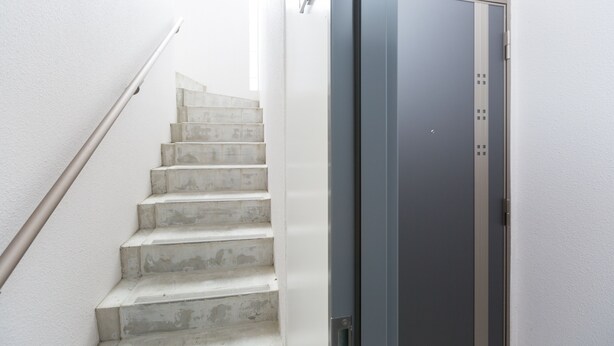Una escala amb barana que condueix a una porta amb mànec metàl·lic.