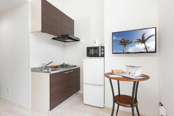 A modern kitchen with a microwave, refrigerator, and a small table with a chair.