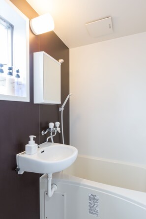 A bathroom with a white sink, a mirror, and a shower.