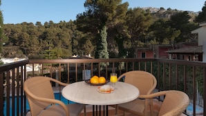 A balcony with wicker chairs, a round table, a bowl of oranges, and a glass of orange juice. - PINOS ALTOS 12. Lovely 1 bedroom apartment in Cala San Vicente (Cala San Vicente)