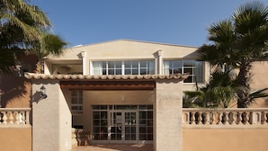 A two-story building with a beige facade, large windows, and a tiled entrance. - PINOS ALTOS 12. Lovely 1 bedroom apartment in Cala San Vicente (Cala San Vicente)
