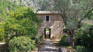 Un edificio rústico de piedra con tejado de tejas, una entrada arqueada y una ventana pequeña.