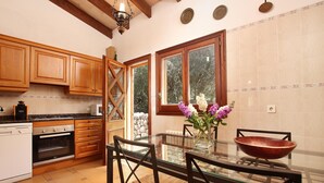 Une cuisine avec des meubles en bois, une table à manger en verre et une vue sur l’extérieur.