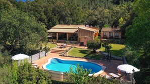 Une villa avec piscine, entourée d’une végétation luxuriante et dominant un paysage montagneux.