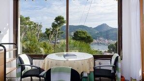 A balcony with a table and chairs, overlooking a scenic view of a coastal town and mountains. - YourHouse Binifat, spacious house overlooking Puerto de Andratx (Andratx)