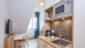 A compact kitchenette with a microwave, coffee maker, and sink. - VR-Serviced Apartments Obergeis (Neuenstein)