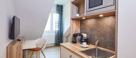 A compact kitchenette with a microwave, coffee maker, and sink.