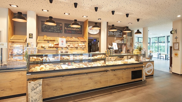 A bakery display with various baked goods and a sign indicating a 450-year-old brand. - VR-Serviced Apartments Obergeis (Neuenstein)