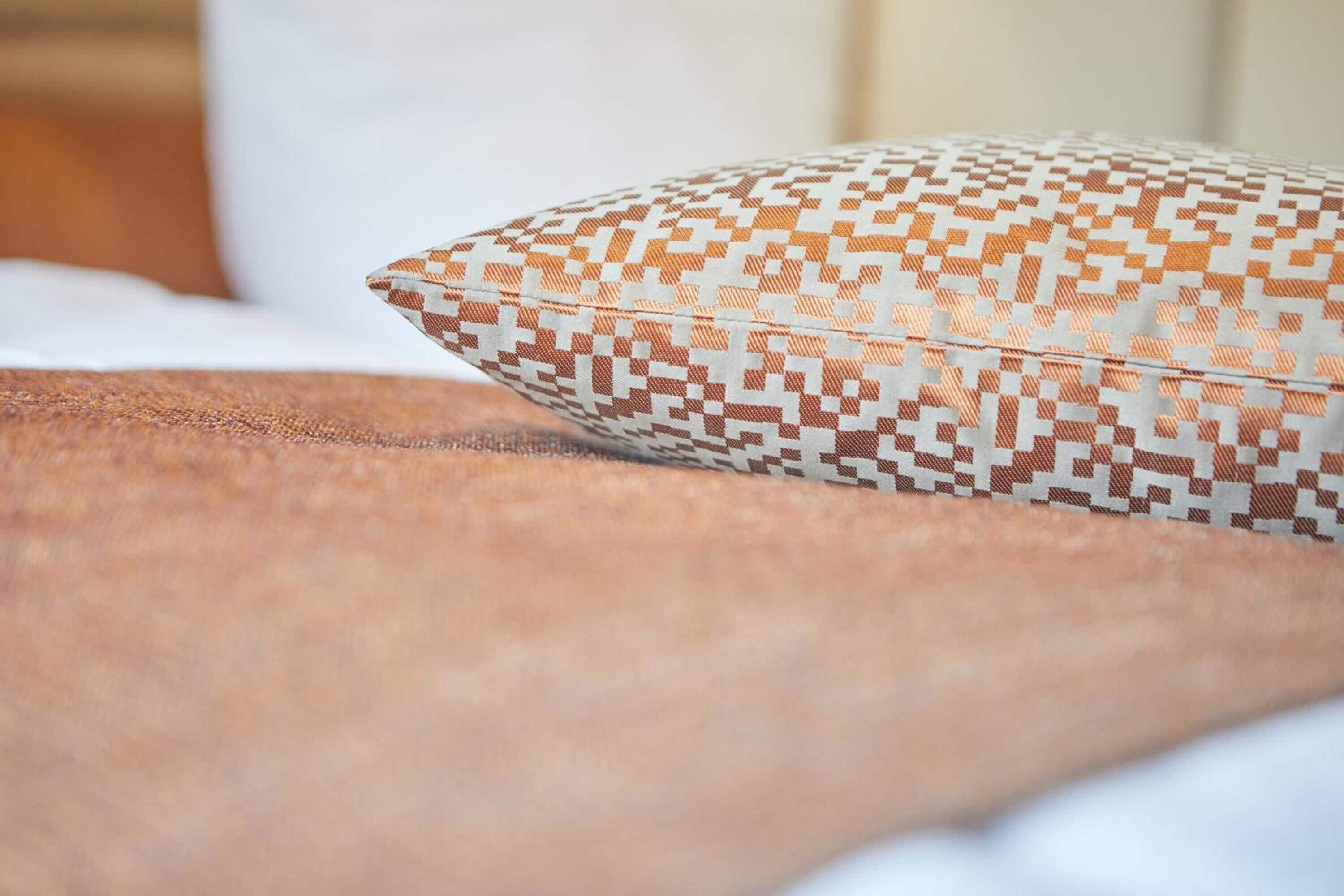 Un gros plan d’un coussin à motifs posé sur un lit.
