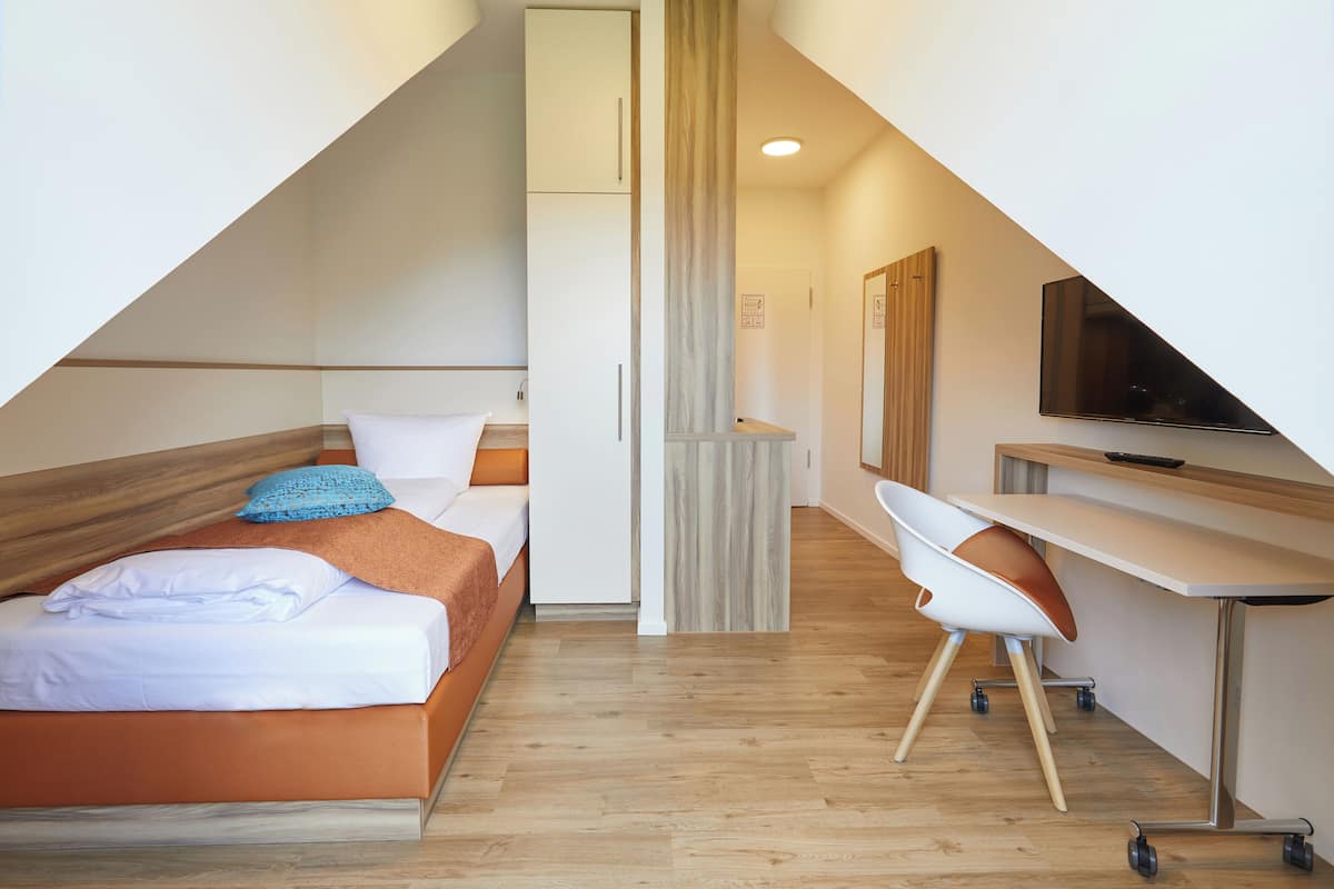 Una habitación de hotel moderna con una cama, un escritorio y un televisor.