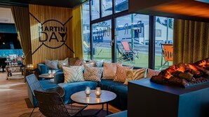 Un coin salon accueillant avec un canapé bleu, des coussins à motifs, une table ronde décorée de bougies et un foyer.