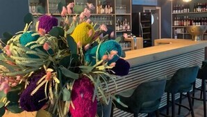 Un espace bar doté d’un comptoir central, de sièges et d’un vase décoratif contenant des fleurs colorées et aux textures variées.