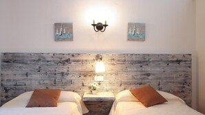 A hotel room with two beds, a wooden headboard, a nightstand with a lamp, and two wall-mounted paintings. - CAN MORANTA (PEDRO MONJO). Complete peace-of-mind among woods (Pollensa)