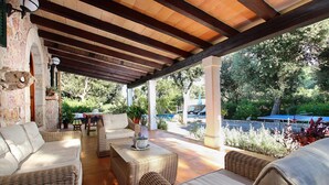 An outdoor covered patio with wicker furniture, stone walls, and a view of the surrounding greenery. - CAN MORANTA (PEDRO MONJO). Complete peace-of-mind among woods (Pollensa)