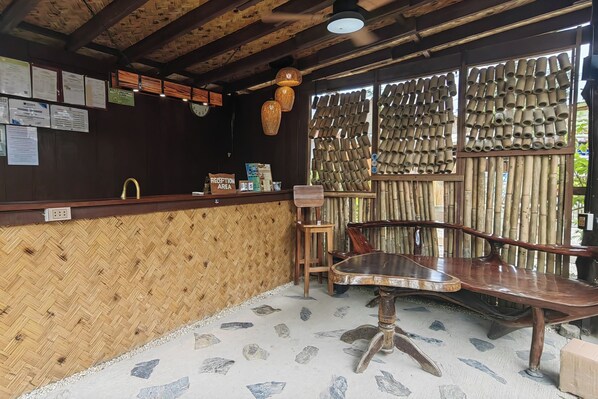 A reception area with a bamboo wall, a reception desk, a wooden bench, and a tiled floor.