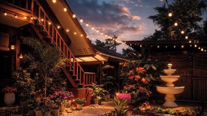 A courtyard with a wooden staircase, string lights, potted plants, and a fountain. -  BING-VICE TOURIST INN Port Barton (San Vicente)