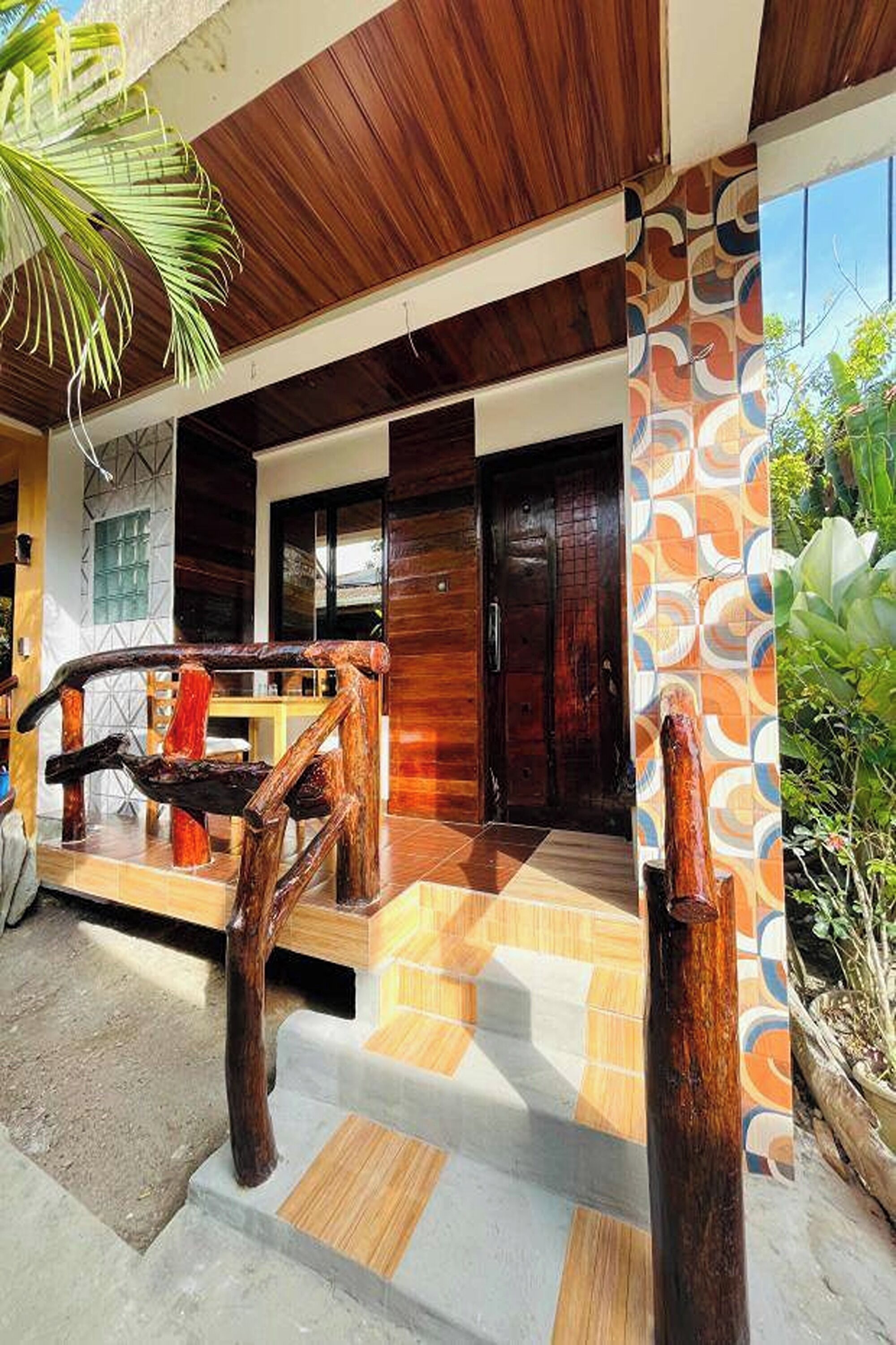 A modern building with a wooden facade, a tiled entrance, and a palm tree.