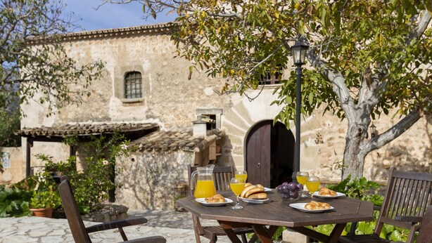 An outdoor dining area with a rustic stone table, wooden chairs, and a stone wall in the background. - PLANA MORRO.  Characterful finca in beautiful countryside near Pollensa (Pollensa)