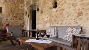 A rustic stone wall interior with a wooden table, two chairs, a sofa, and a wine bottle. - PLANA MORRO.  Characterful finca in beautiful countryside near Pollensa (Pollensa)