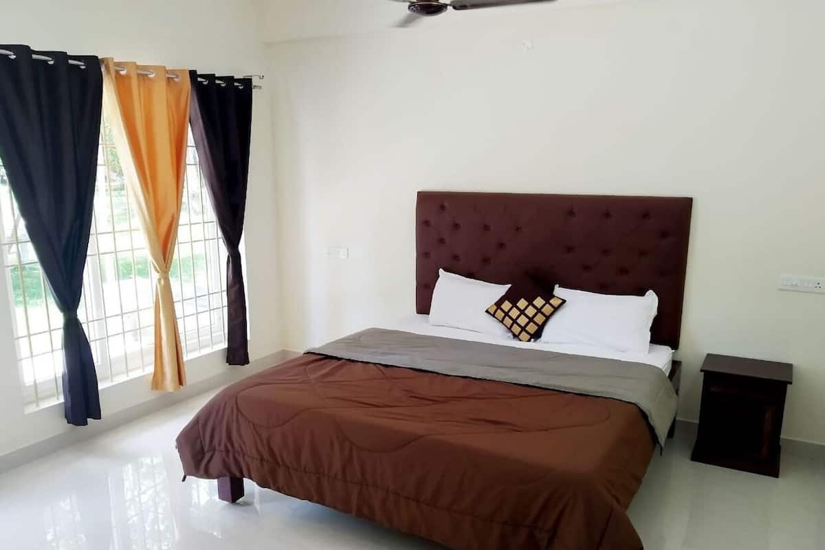 A bedroom with a bed, curtains, a nightstand, and a ceiling fan.