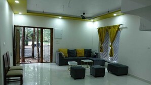 A modern living room with a sofa set, ottomans, a coffee table, and a chair. - Nature Breeze Resort (Vanur)