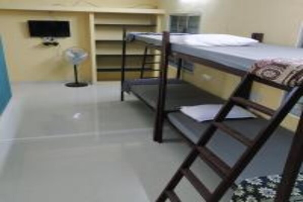 A bunk bed room with a television, a fan, and a window.