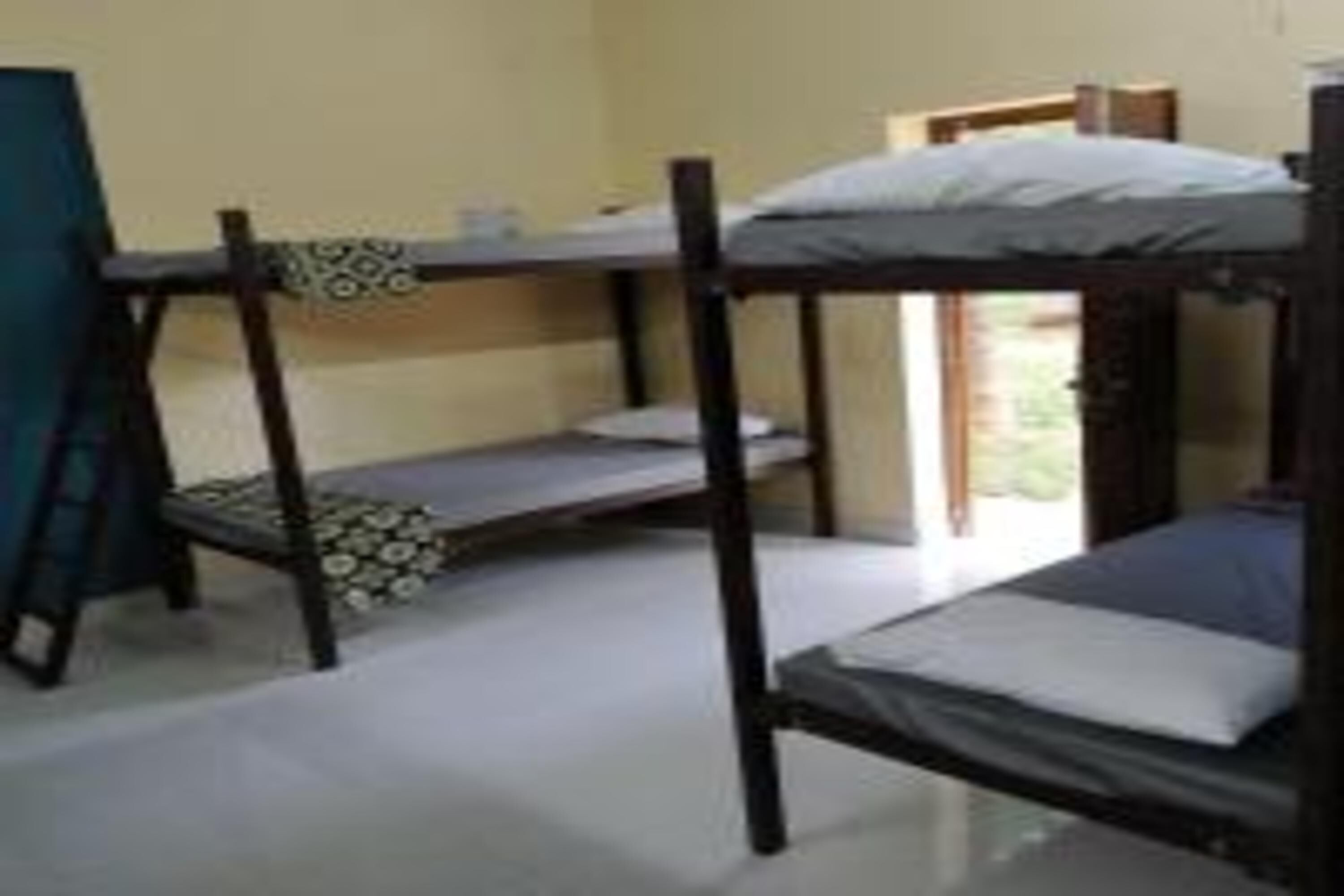A dormitory room with bunk beds, a small table, and a window.