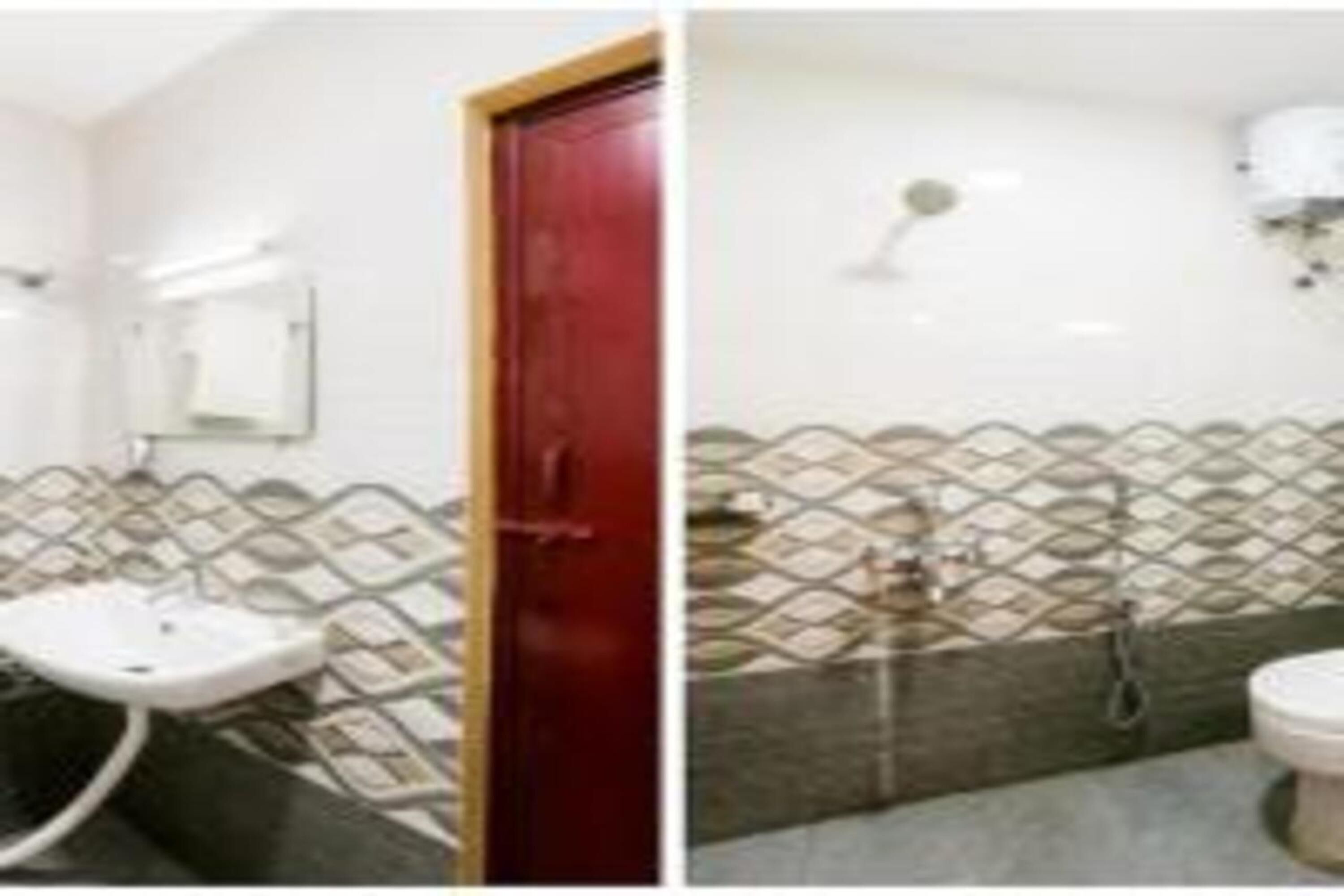 Un baño con un lavabo blanco, una puerta roja y un papel tapiz estampado.
