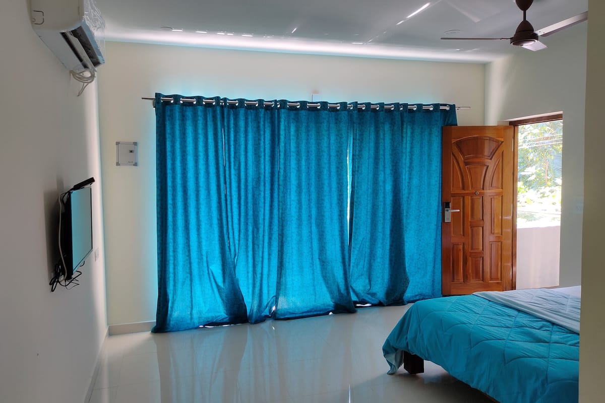A bedroom with a bed, a ceiling fan, and a window with curtains.