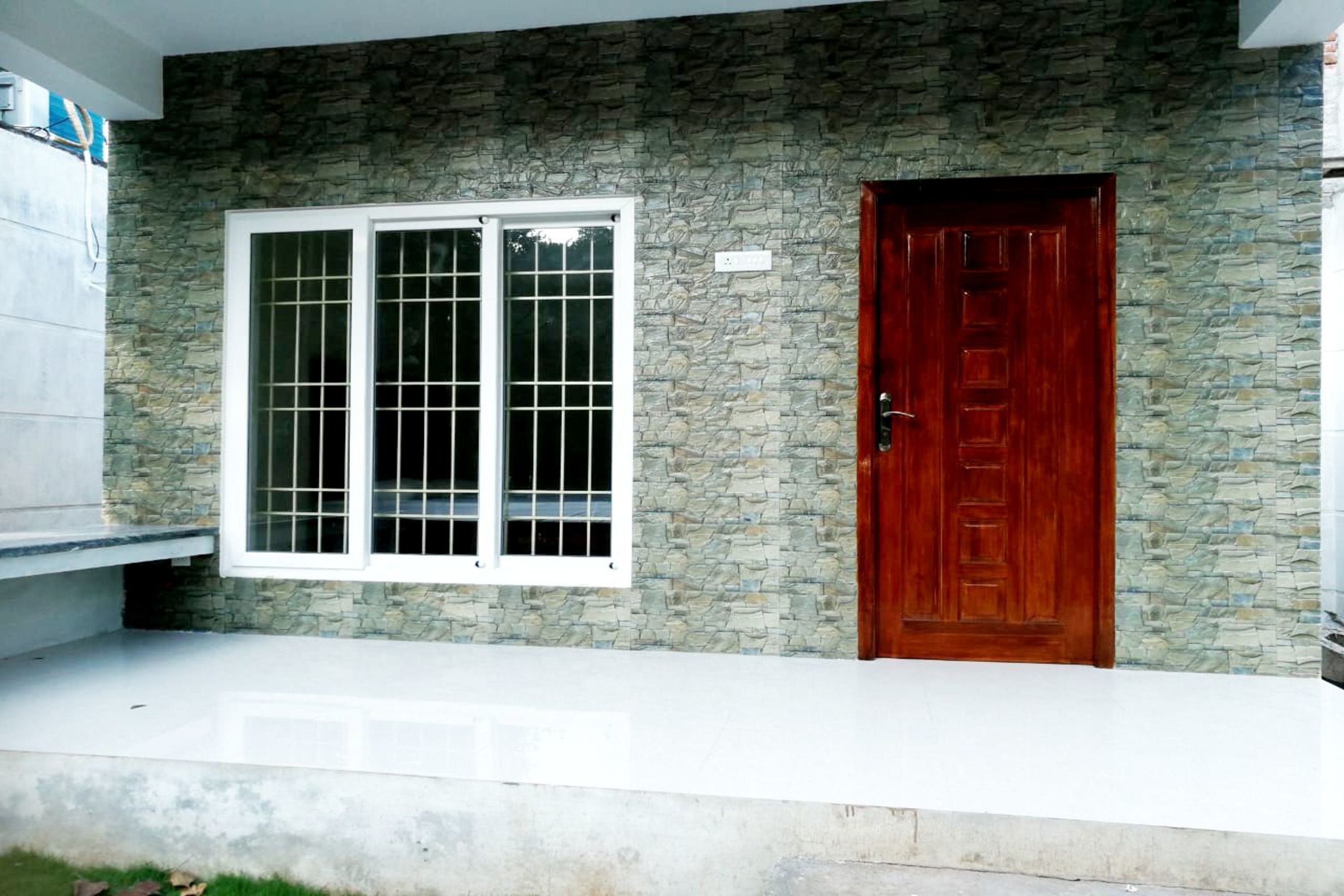Ein Haus mit Steinfassade, einem großen Fenster mit weißem Rahmen und einer Holztür.